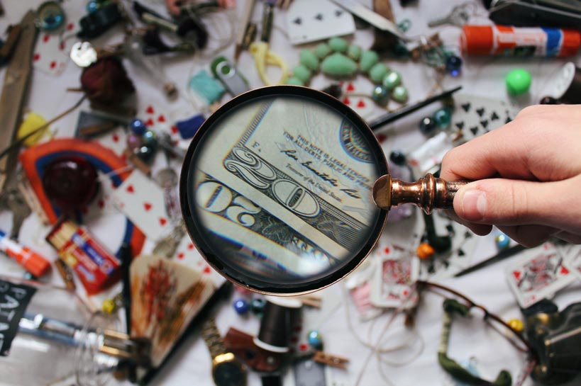 Magnifying glass finding money amidst unorganized items